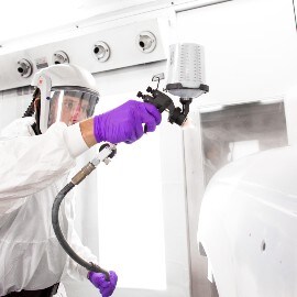 Male Painter spraying primer on a car body part using a 3M Performance Spray Gun system