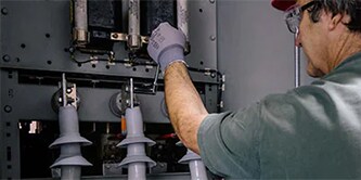 A man monitors electrical components to keep the grid working reliably and efficiently.
