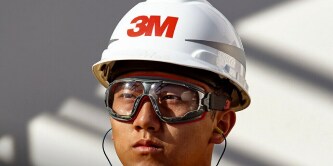 Industrial worker using fall protection gear while performing elevated maintenance on a facility structure.
