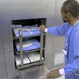 A central sterilisation person pushes the instrument trolley into the sterilizer