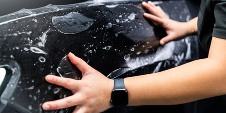 Person applying paint protection film to a car
