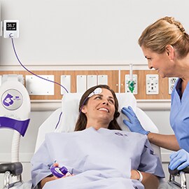 A nurse checks on a patient laying in a hospital bed