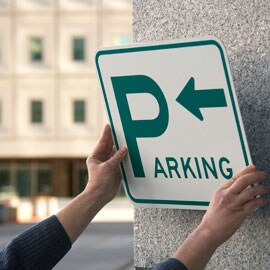 Person mounting parking sign to concrete wall