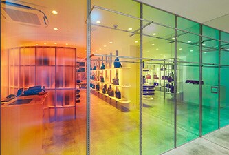 Retail windows with 3M Dichroic Glass finishes showing green, yellow, orange and red tones. 
