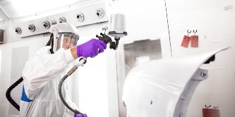 Male painter spraying primer on a car area using the 3M Performance spray gun
