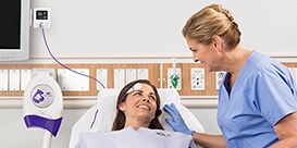 A nurse checks on a patient laying in a hospital bed
