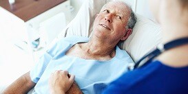 Patient in a hospital bed holding a nurse's hand
