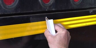 Person applying conspicuity tape to truck
