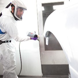 Male painter spraying a white car body part using a 3M Spray system