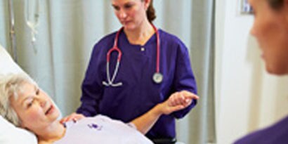 A nurse checks on an elderley patient
