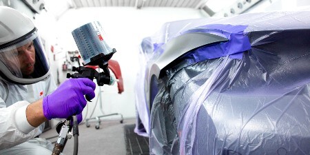 male painter spraying on a car with a 3M spray gun sytem
