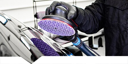 Technician sanding a damaged car panel
