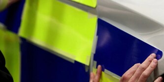 Person applying reflective sheeting to a police car
