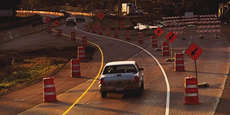Cars driving through road construction work zones.
