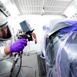 Painter spraying on a car area using a performance spray gun from 3M