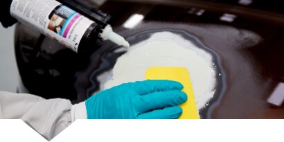 Technician applying filler to damaged car panel
