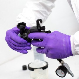 Hands with purple gloves setting an atomizing head of a 3M Performance Spray Gun