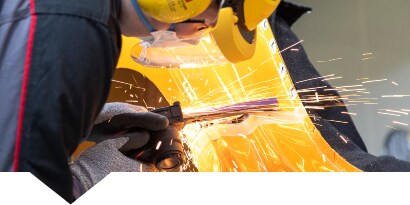 Technician cutting a metal car body part
