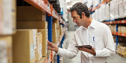 Man in a warehouse looking at a box on a shelf
