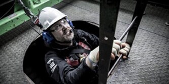 Worker wearing 3M safety equipment is  crawling up a ladder

