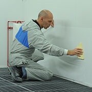 Man applying the dirt trap protection material on a wall with a spreader