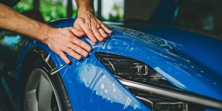 Person applying paint protection film to a car
