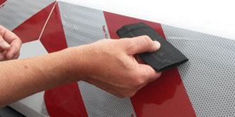 Person applying chevron markings to a van
