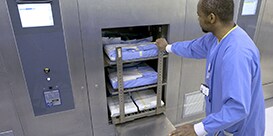 A central sterilisation person pushes the instrument trolley into the sterilizer
