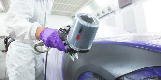male painter spraying paint on a car area using the 3M performance spray gun
