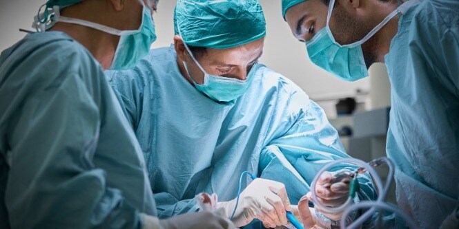 three surgeons operating patient for breast implant
