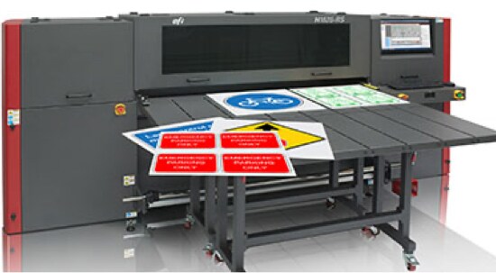 A dark grey digital sign printer with printed signs sitting on its flatbed.