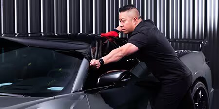 Wrap installer applying film to the roof of a vehicle.
