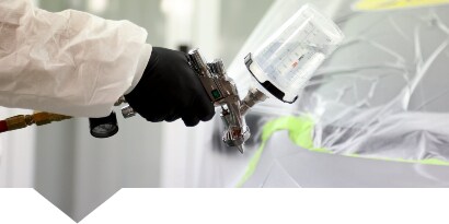 Painter applying paint to a repaired car panel
