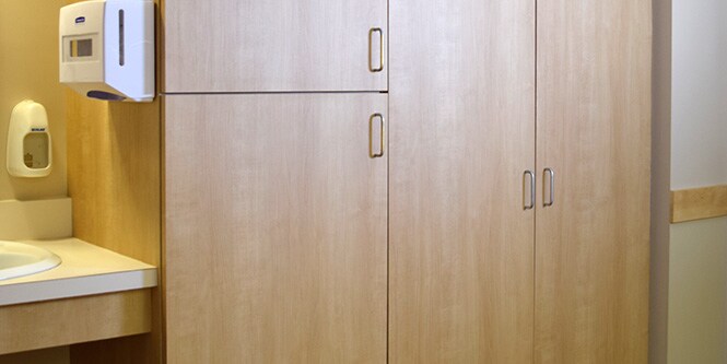 Image of hospital room sink and storage cabinet area that has been refurbished with light wood-toned 3M DI-NOC Architectural Film
