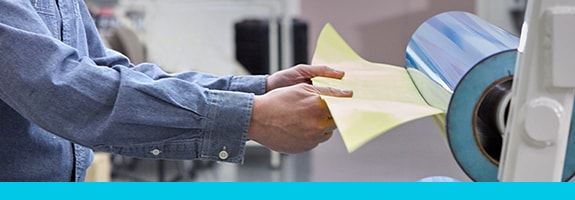 Worker removing flexographic tape from a cylinder