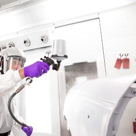 Male painter spraying primer on a car body part using a 3M Spray Gun system