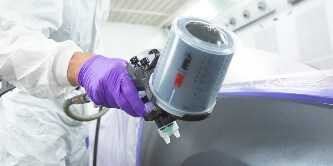 Painter spraying paint on a car area using the 3M performance spray gun
