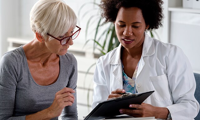 A doctor and patient looking at a clipboard
