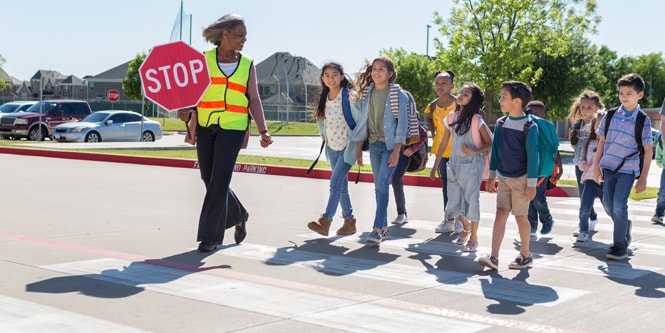 School kids crossing the road on a pedestrian crossing
