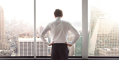 A man looks out of a sunny office window of a building covered with 3M™ Sun Control Window Film.
